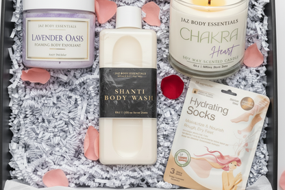Assorted Jaz Body Essentials products including a bottle, candle, and packaging on a textured surface with pink petals.