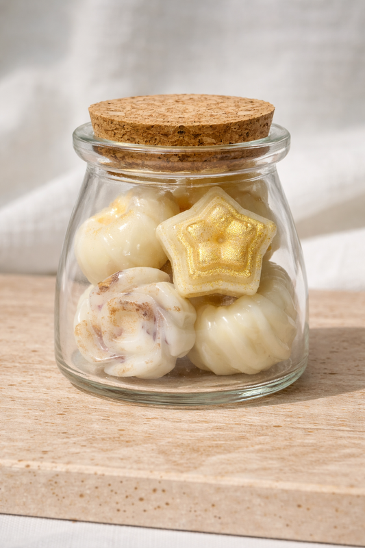 Glass jar with cork lid containing star-shaped and round white candies on a wooden surface.