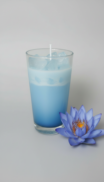Glass with blue liquid and a candle on a gray background