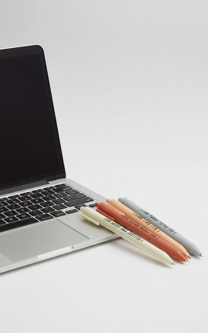 Laptop with four colorful pens on a light surface