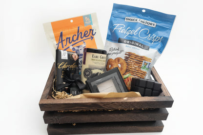 Gift basket with snacks and chocolate on a wooden surface