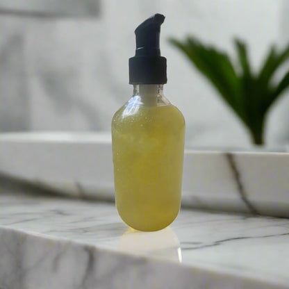 Clear bottle with yellow liquid and black cap on a concrete surface outdoors.
