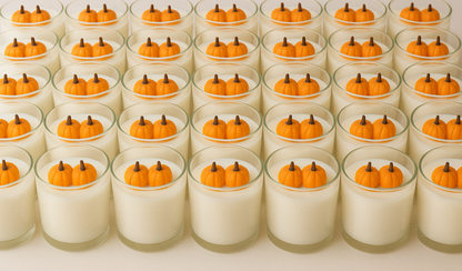 Multiple small glass containers with white candle wax and orange pumpkin decorations on a white background
