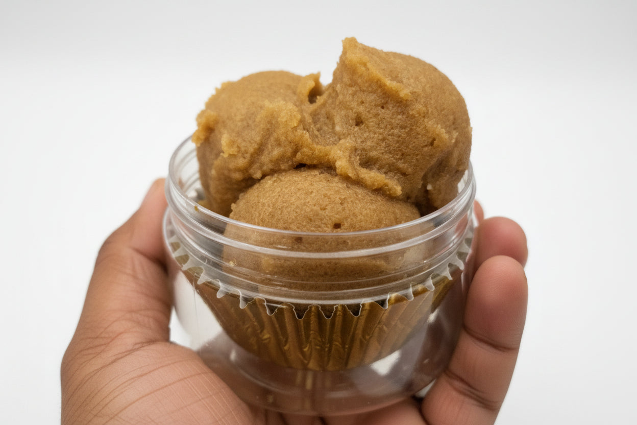 Close-up of a container with brown paste being scooped out by a hand.