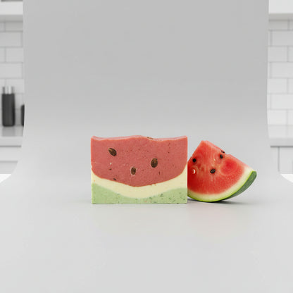A bar of Summer-Melon Artisan Soap with a brown top layer and a green bottom layer, placed on a surface with natural light in the background.